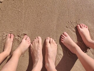 Pies en la arena de la playa, familia en la playa