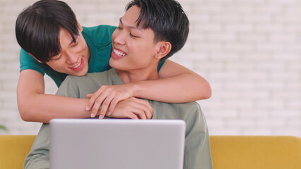 Asian gay takes care of his partner while working on his laptop at home.