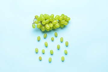 Cloud and rain drops made of green grapes on color background