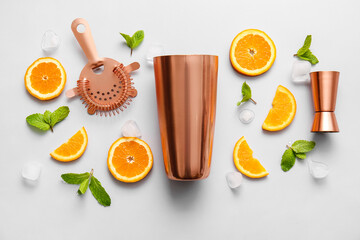 Copper strainer, cobbler shaker, double jigger and cocktail ingredients on grey background