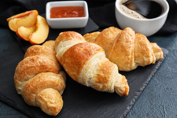 Board of delicious croissants on black background