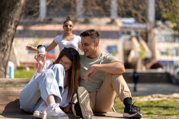 Joyful couple sitting on the wooden bench in park