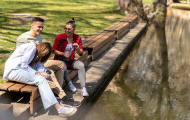 Three happy friends talking taking a conversation near water