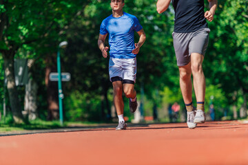 Fototapeta premium Two healthy young men running in the park on a sunny day..