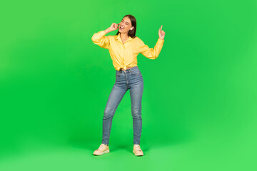 Fototapeta na wymiar Female Listening To Music In Earbuds Dancing, Green Background
