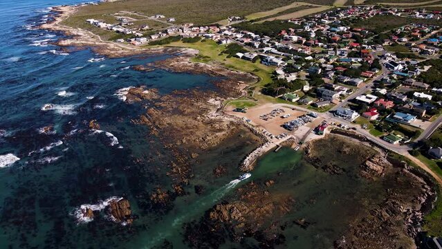 Shark cage diving boat navigates narrow channel through rocky shallows; aerial