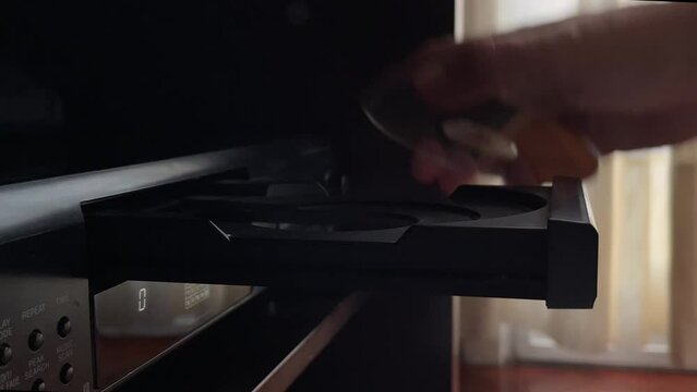 A hand removes a cd from the vintage cd player
