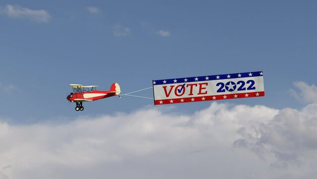 Biplane flying in the clouds pulling a banner which says, "VOTE 2022".