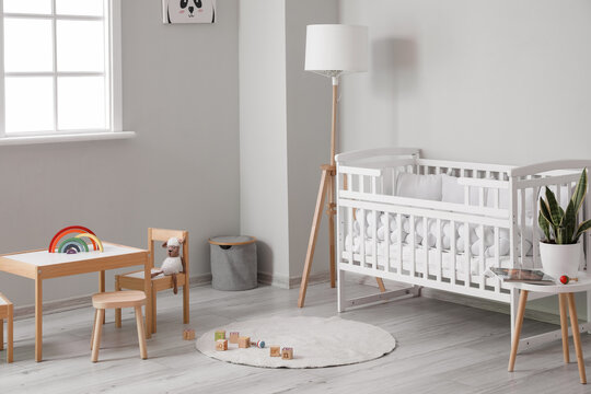 Interior of light nursery with baby crib, lamp and toys