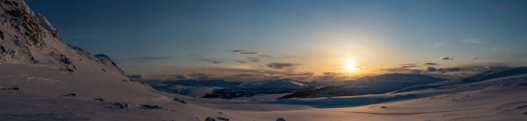 Panoramic sunset, golden light over Norwegian snowy winter mountains. Joesjo, Sweden