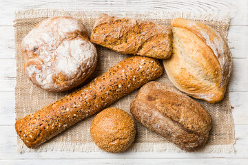 Assortment of freshly baked bread with napkin on rustic table top view. Healthy unleavened bread. French bread