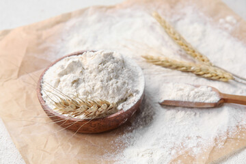 Bowl with wheat flour and scoop on parchment