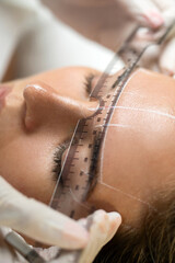 Woman during professional eyebrow mapping procedure
