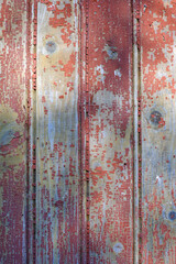 wooden panel of an abandoned house with remnants of red paint