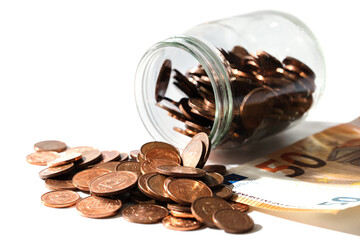 Fifty euro banknote and shiny copper low value coins spilled from a glass jar.