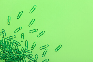 Green paper clips on color background