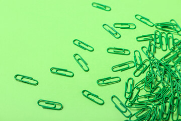 Green paper clips on color background