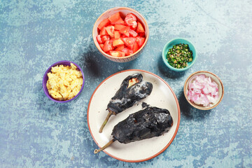 barbeque of brinjal ready to cook with chopped tomatoes, onions, chilies and fried egg 