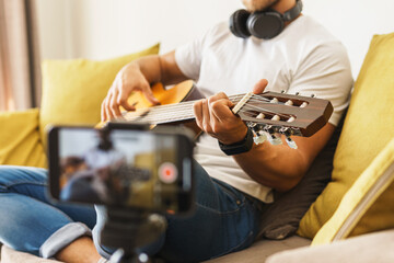 Musician blogger on sofa playing acoustic guitar