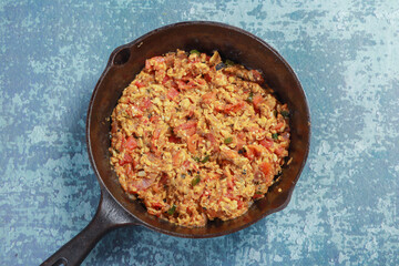 frying chopped tomatoes, onions, chilies, egg and barbequed brinjal together
