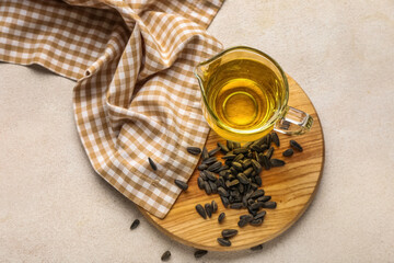 Jug of oil, sunflower seeds, napkin and board on light background