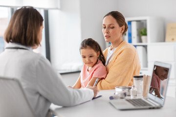 Obraz premium medicine, healthcare and pediatry concept - mother with little daughter talking to doctor at clinic