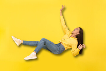 Scared Millennial Lady Falling In Mid-Air Shouting Over Yellow Background - obrazy, fototapety, plakaty