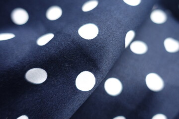 Close shot of fold on dark blue and white cotton fabric with polka dot pattern