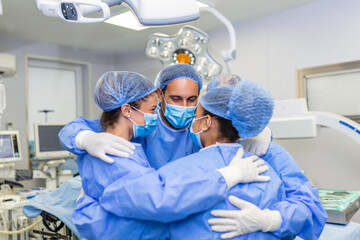 Medical professionals embracing each other in ICU. Doctors and nurses are in protective coveralls after successful treatment. They are at hospital during COVID-19.