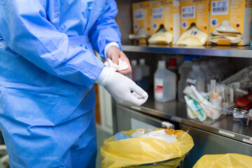 Male surgeon removing surgical gloves in operation theater at hospital