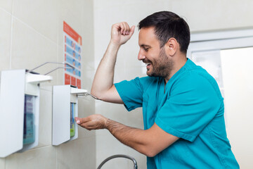 Doctor washing hands with soap. Male surgeon is preparing for surgery. He is in uniform at operating room.