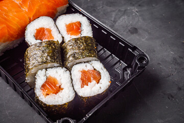 delicious sushi rolls in a delivery box on a black background