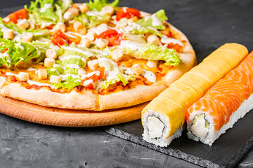 set of pizza and sushi rolls on a dark stone background