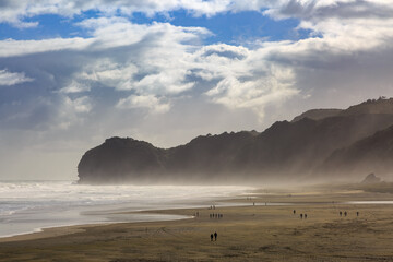 The black sand beach at Piha, New Zealand, with a strong wind blowing sand inshore. At the end of...