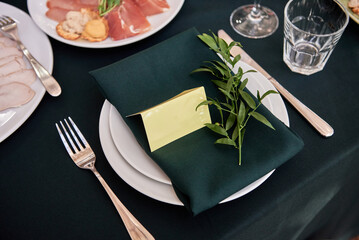 Table setting with sparkling wineglasses, plate with green napkin and cutlery on table, copy space. Place set at wedding reception. Table served for wedding banquet in restaurant