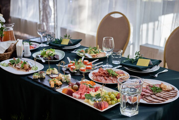 Table setting with sparkling wineglasses, plate with green napkin and cutlery on table, copy space. Place set at wedding reception. Table served for wedding banquet in restaurant