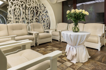 Cozy waiting area in restaurant with sofas and armchairs decorated with flowers