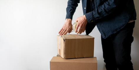 person's hands sealing big cardboard box with tape for shipment.