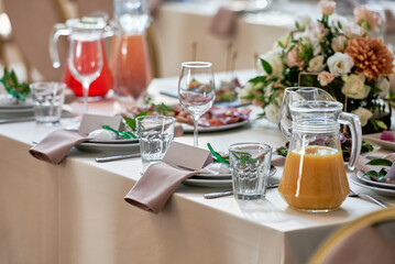 Table setting with sparkling wineglasses, plate with beige napkin and cutlery on table, copy space. Place set at wedding reception. Table served for wedding banquet in restaurant