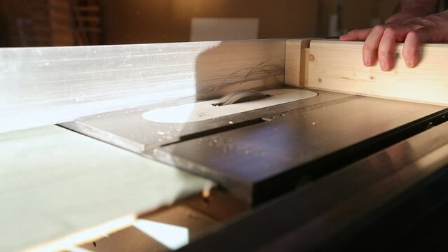 A craftsman rotates and cuts tenons from a piece of wood using a table saw with a dado set in slow motion.