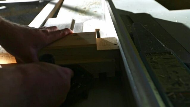A woodworker places a piece of wood on a table saw with a stacked dado set and pushes it through to make multiple cuts to create a tenon in slow motion.