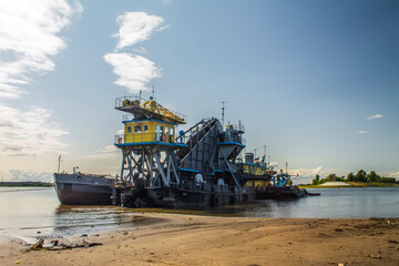 Fototapeta premium A floating dredger in action. Extracts and drains sand into a special barge. A sunny summer day.