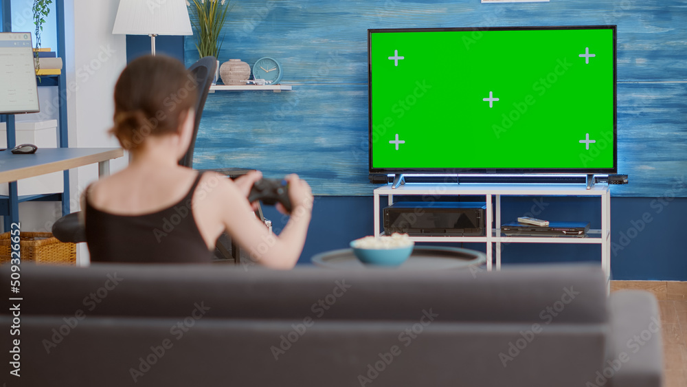 Poster static tripod shot of gamer girl holding wireless gamepad playing action console video game on green