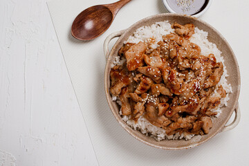Roast pork with teriyaki sauce sprinkled with white sesame seeds on a white background.
