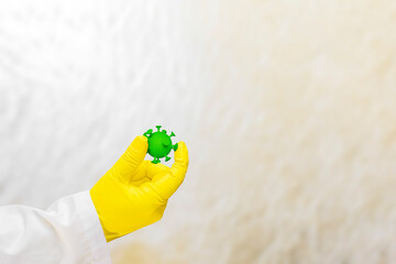 Obraz premium A doctor in a medical gown and protective gloves holds a virus in his hand. The face is not visible. The concept of healthcare and infection protection.