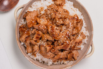 Roast pork with teriyaki sauce sprinkled with white sesame seeds on a white background.