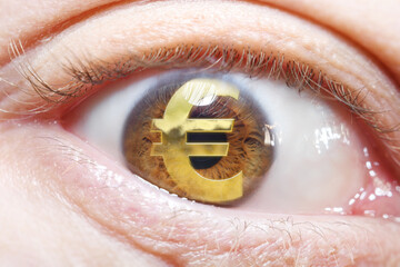 Close-up of an eye in selective focus with a reflection of the euro sign. National currency symbol.