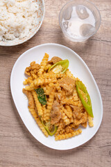 Stir-fried pork with red curry paste and young coconut shoots in a white plate