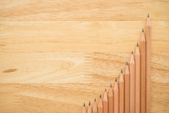 Flat lay of wooden pencils show as graph chart increase up on wooden table background with copy space. Creative idea, education, business, finance profit growth or success target objective concept.