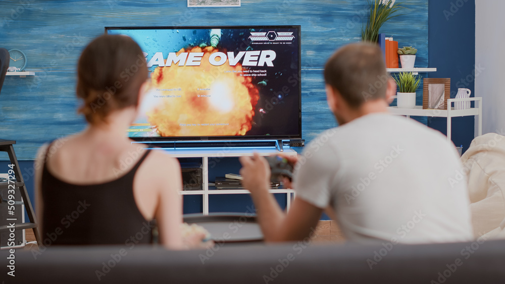 Poster young woman disappointed because of gamer boyfriend losing online game while playing on console usin
